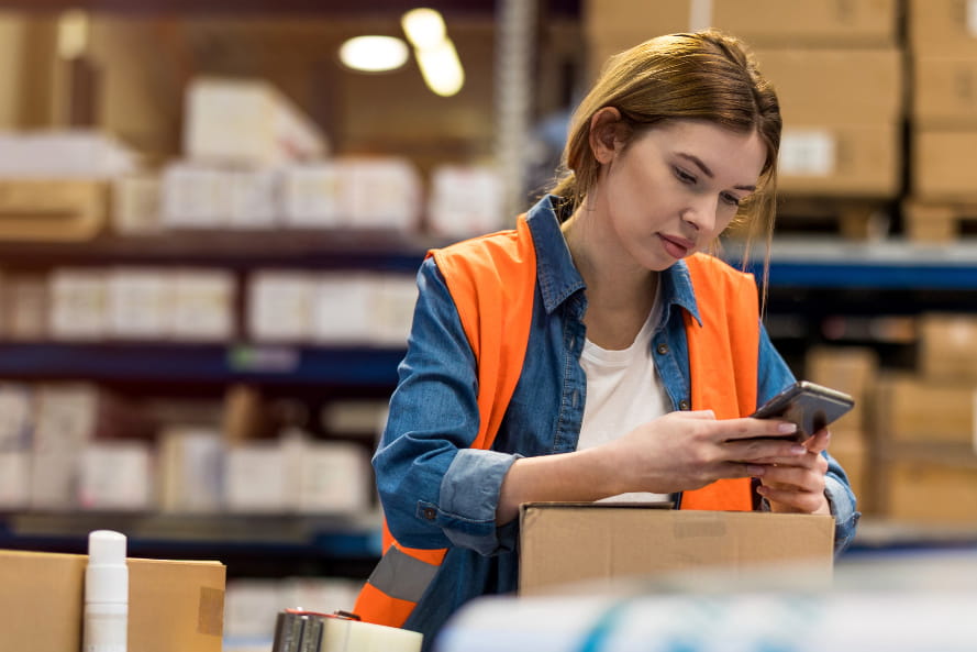 MItarbeiterin mit Smartphone im Logistiklager