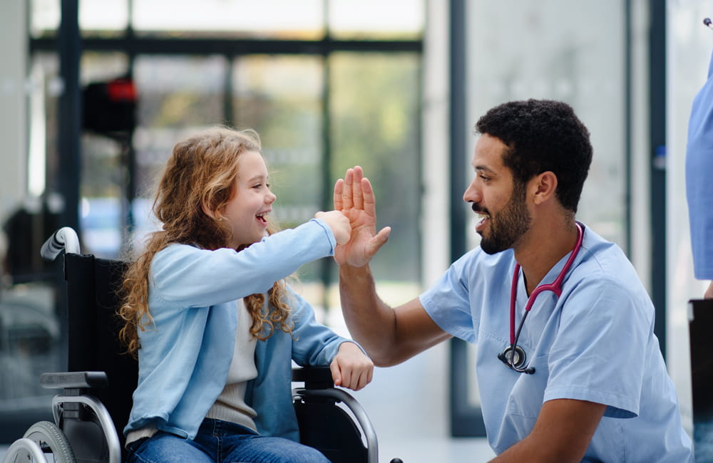 Gesundheits- und Krankenpfleger klatscht ein mit kleinem Mädchen im Rollstuhl.