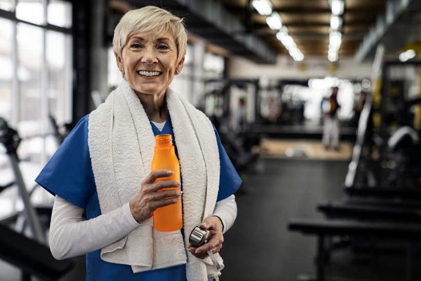 laechelnde-frau-im-fitnessstudio-mit-trinkflasche-in-der-hand-adecco